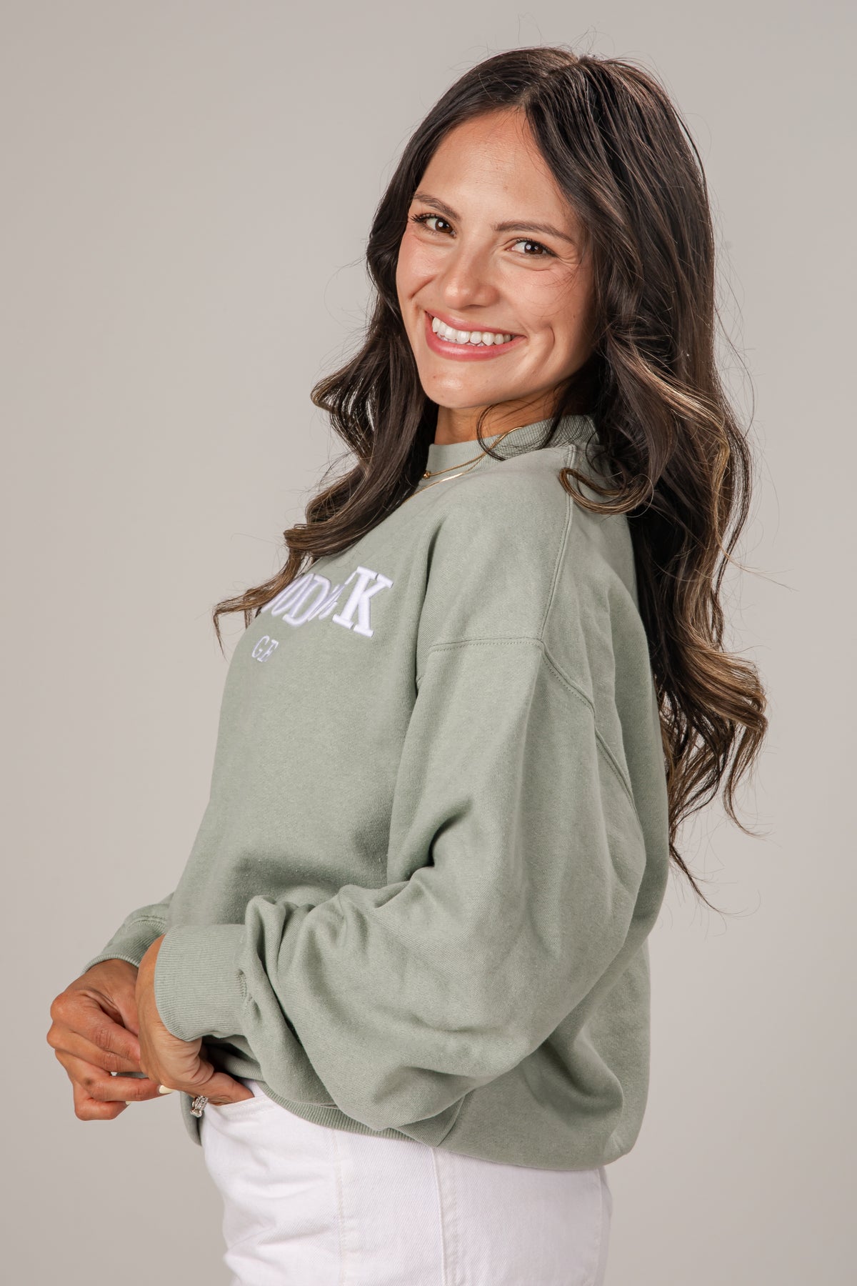 Woman wearing a green sweatshirt with text on a plain background
