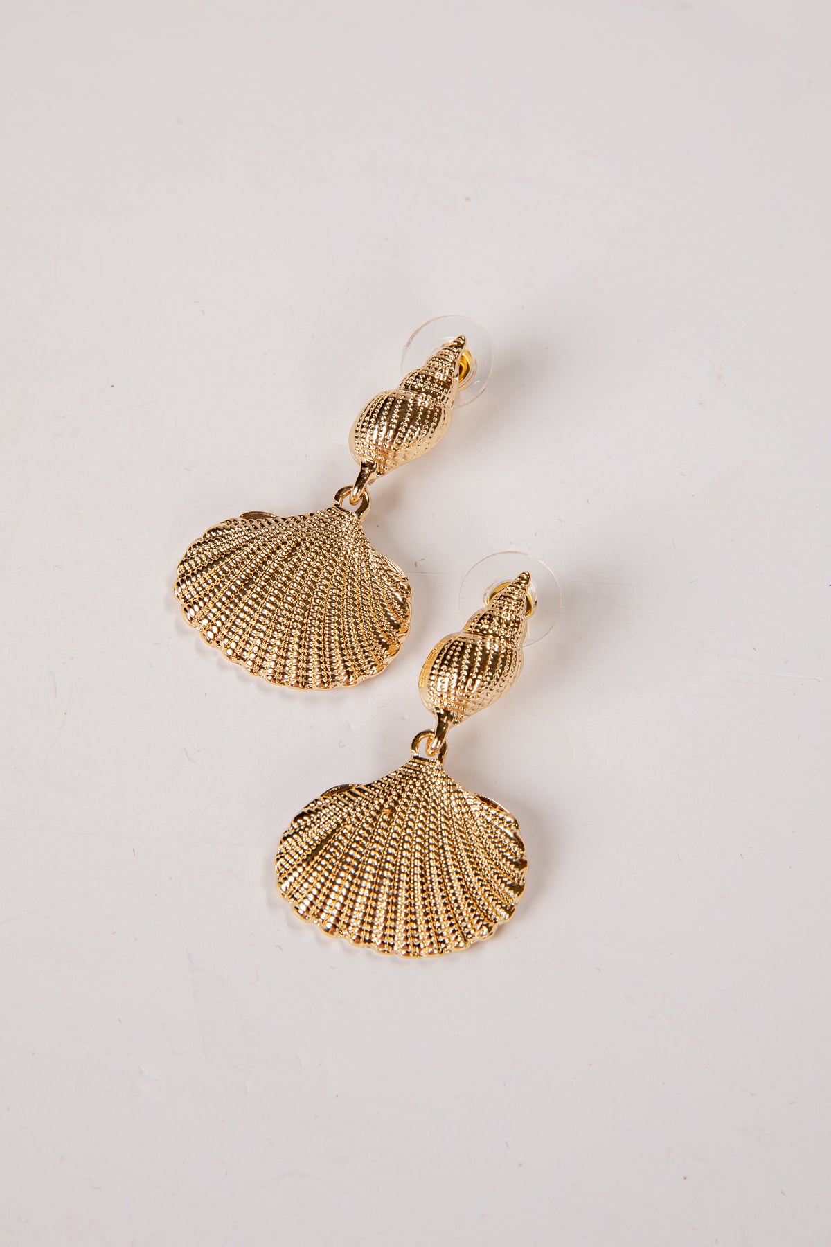 Gold shell-shaped earrings on a light gray background