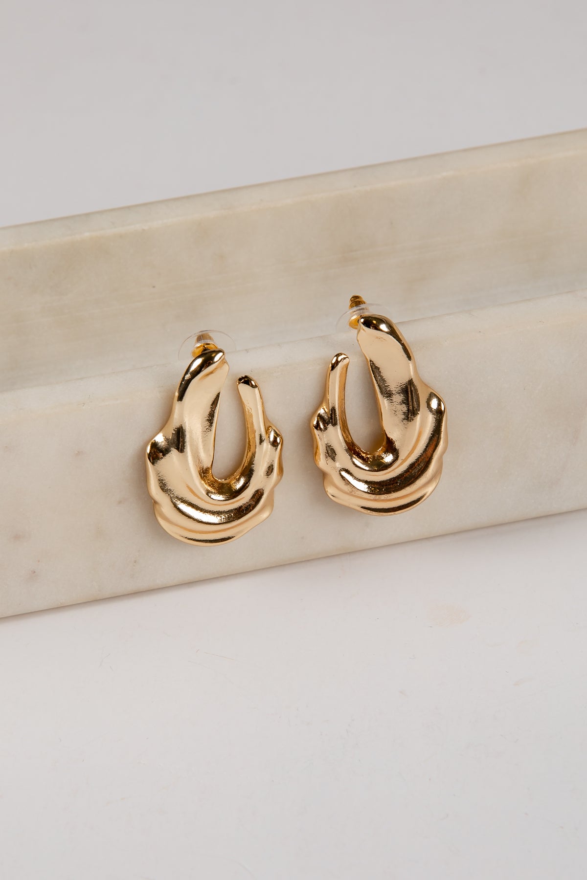Gold hoop earrings on a light beige surface