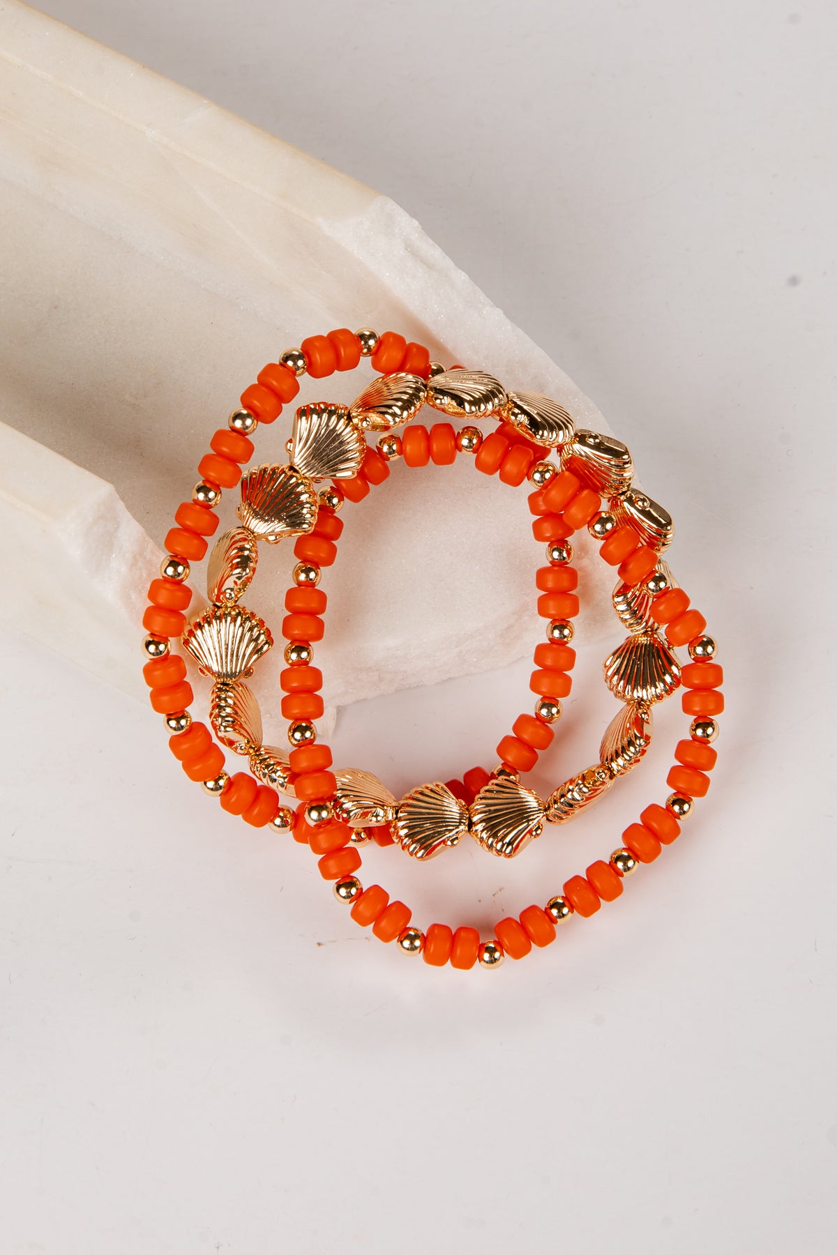 Orange beaded bracelet with gold accents on a light background