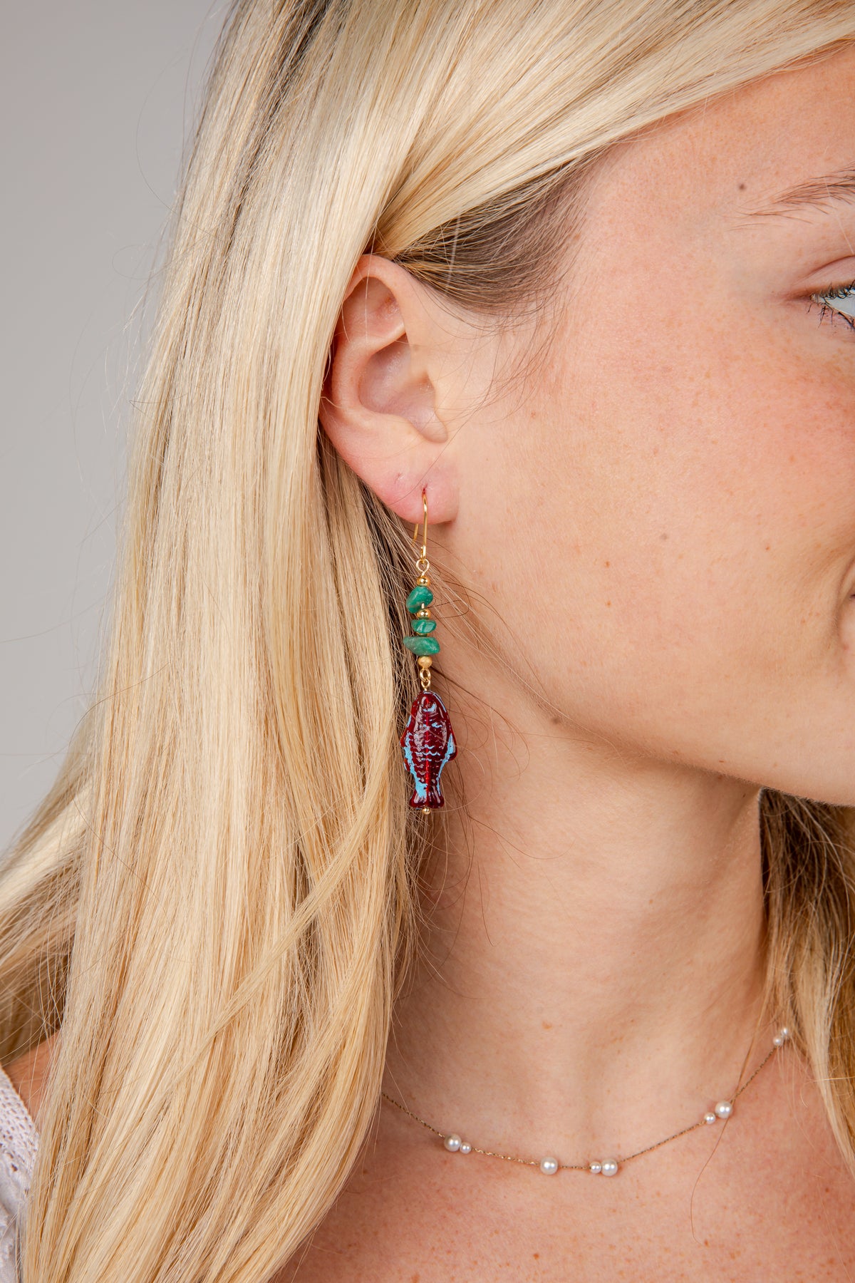 Close-up of a woman wearing a colorful earring with a neutral background