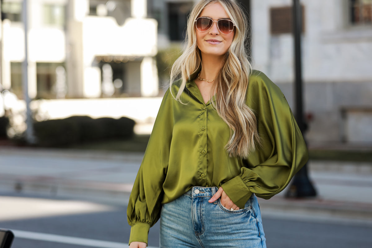 model wearing a trendy green satin button up blouse