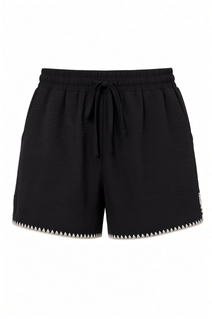 Black textured drawstring shorts with a zigzag cutout detail along the hem, shown against a plain white background.