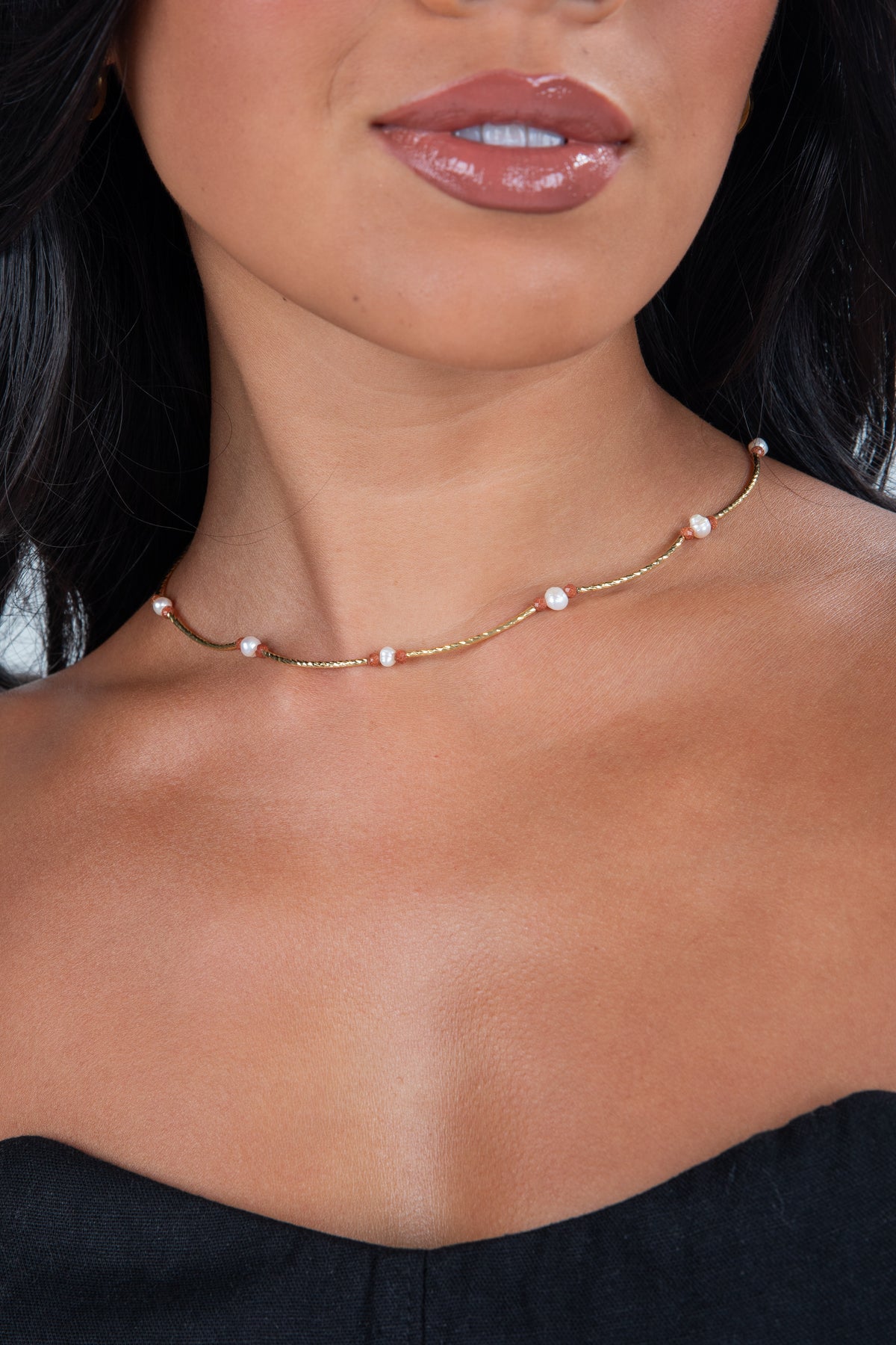 Close-up of a woman wearing a delicate pearl necklace with a blurred background