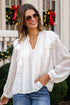 Woman wearing a white blouse and blue jeans standing in front of a decorated house.
