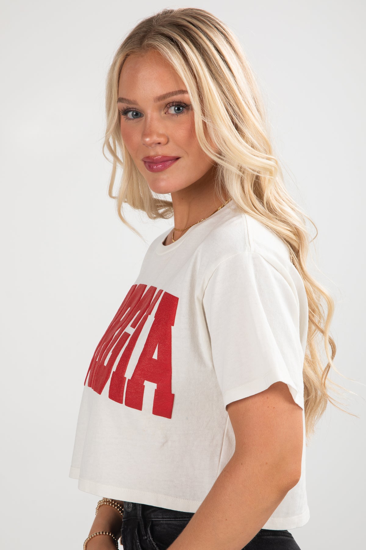 Woman wearing a white t-shirt with red text on a plain background