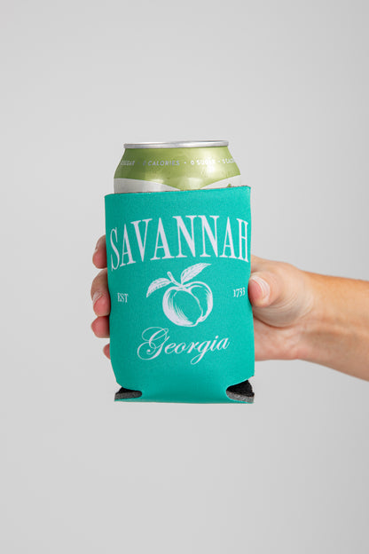 Hand holding a can with a teal sleeve featuring &