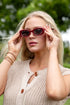 Woman wearing sunglasses with a blurred green background