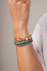 Close-up of a wrist wearing two bracelets with a neutral background