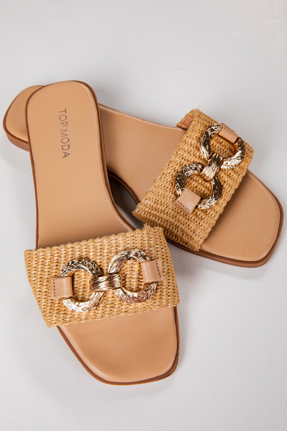 Tan sandals with woven straps and gold chain details on a light gray background