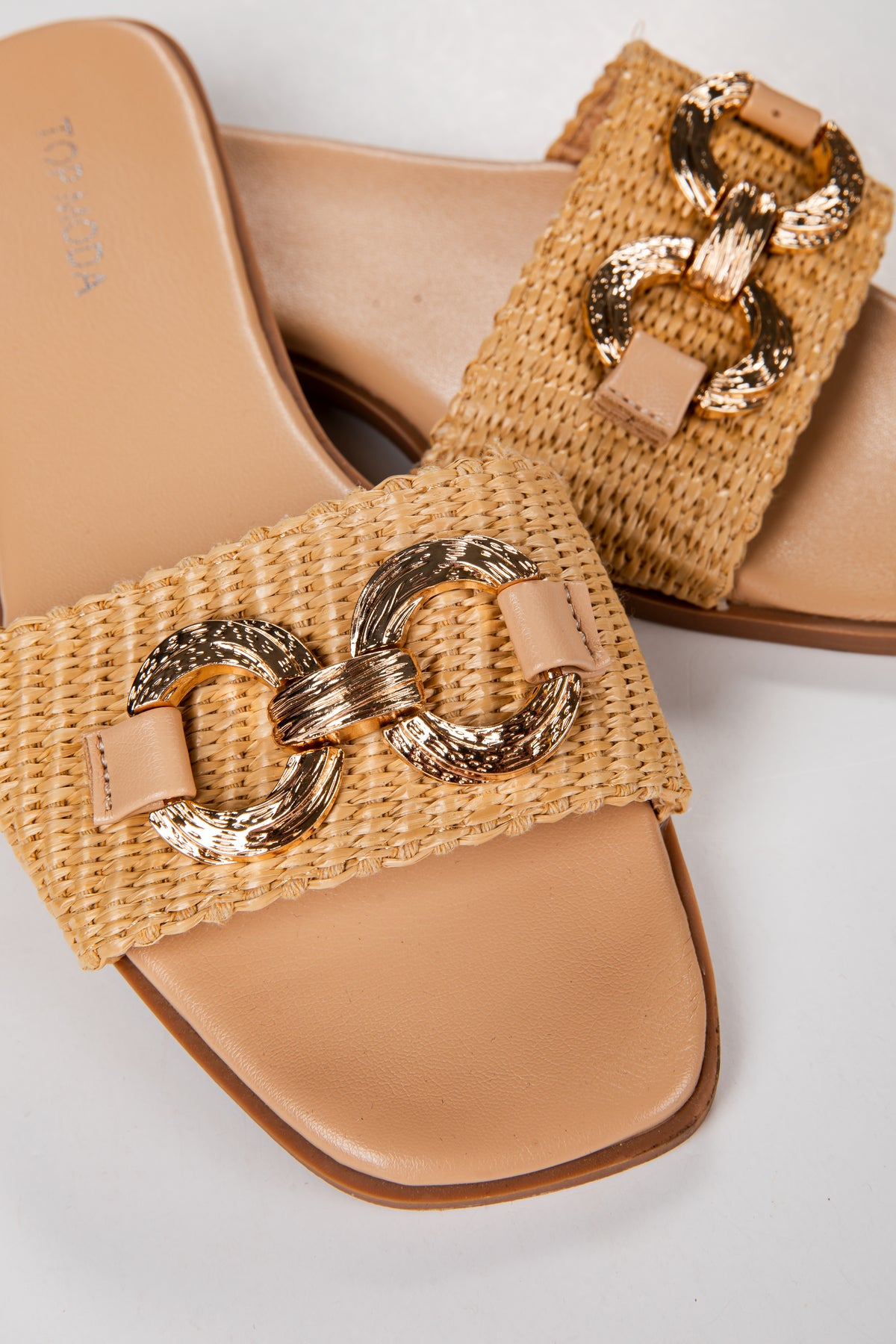 Tan woven sandals with gold chain detail on a light gray background