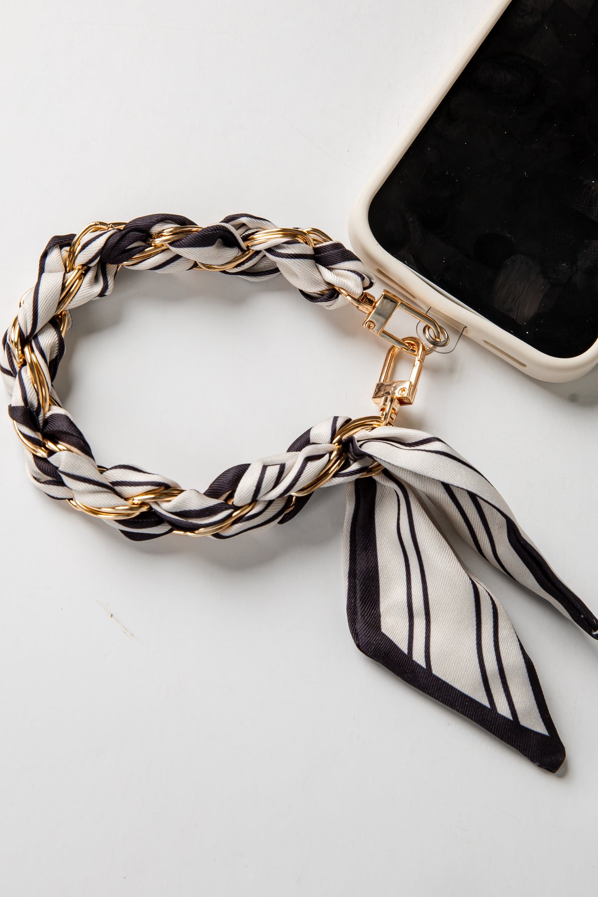 Phone case with a black and white striped scarf accessory on a white background
