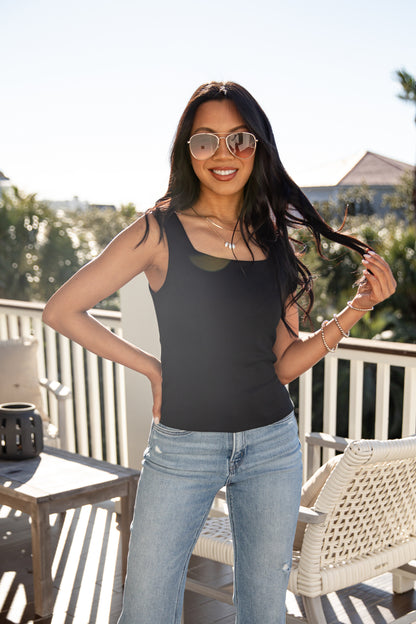 Woman wearing sunglasses and a black tank top on a balcony