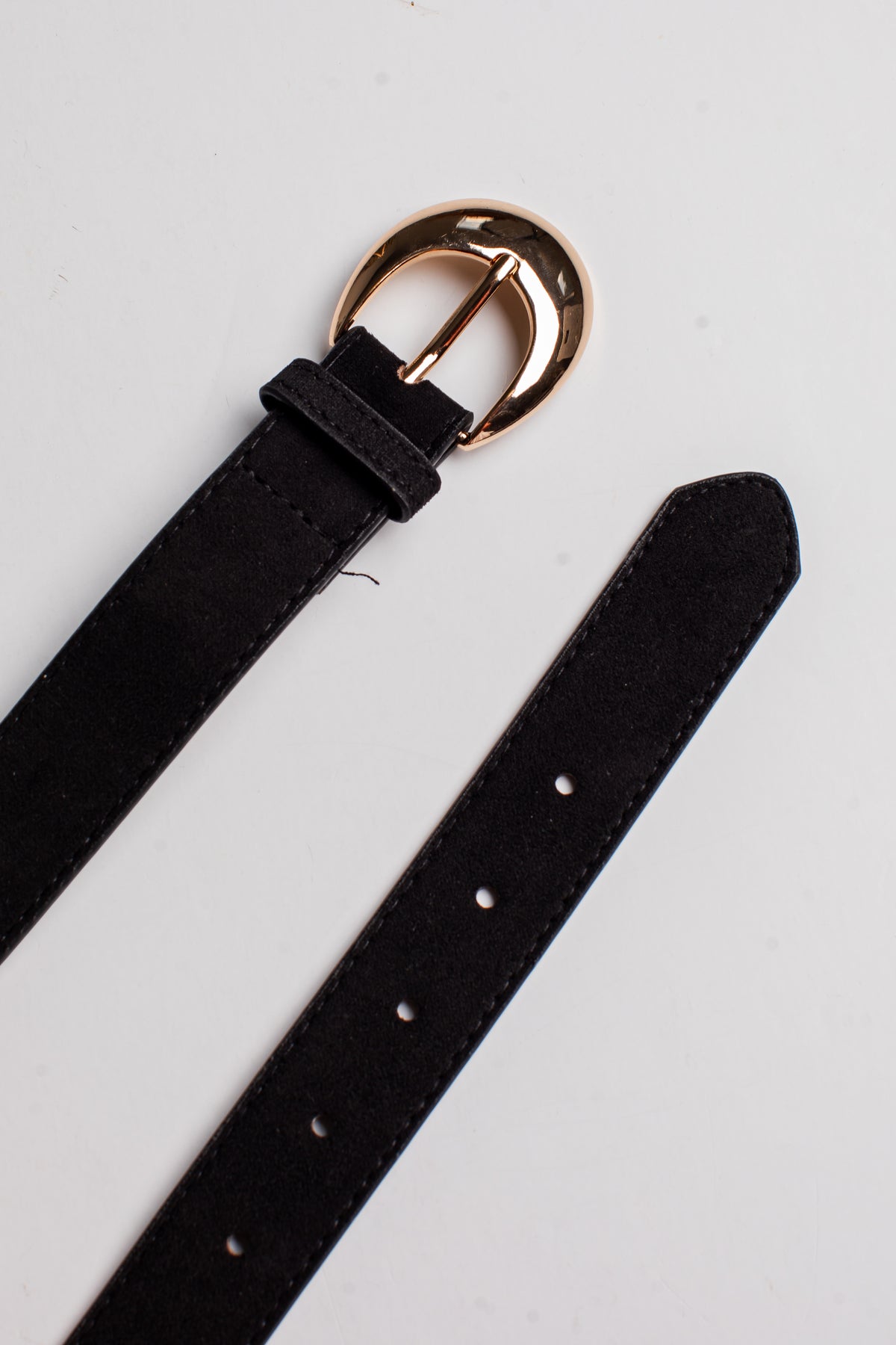 A black suede belt with a polished gold-tone metal buckle, shown laid out diagonally on a clean white background.