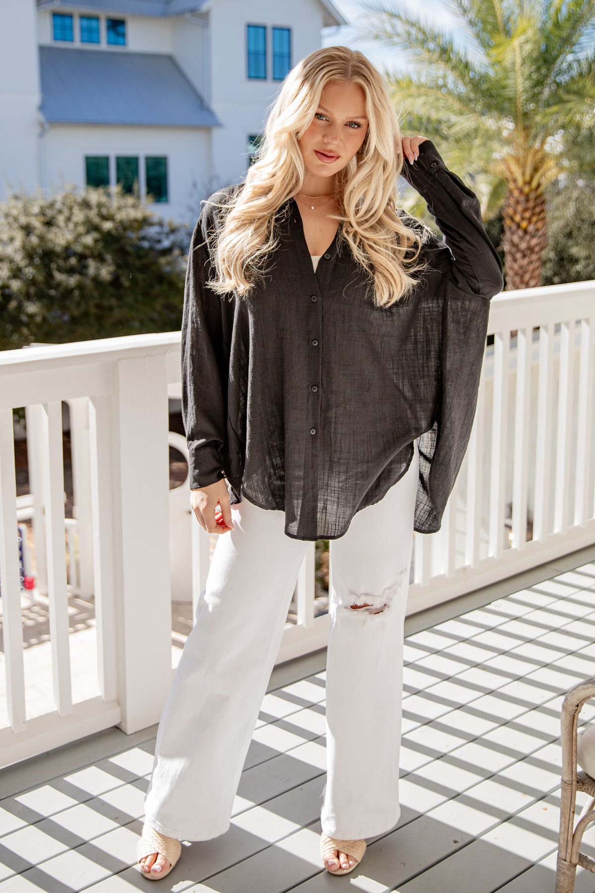 Woman wearing a black shirt and white pants on a balcony