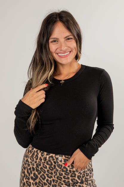 Woman wearing a black long-sleeve top and leopard print skirt on a plain background