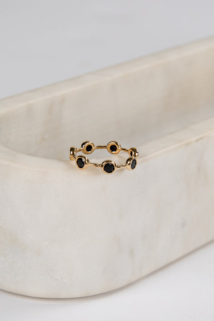 Gold ring with black stones on a beige fabric background