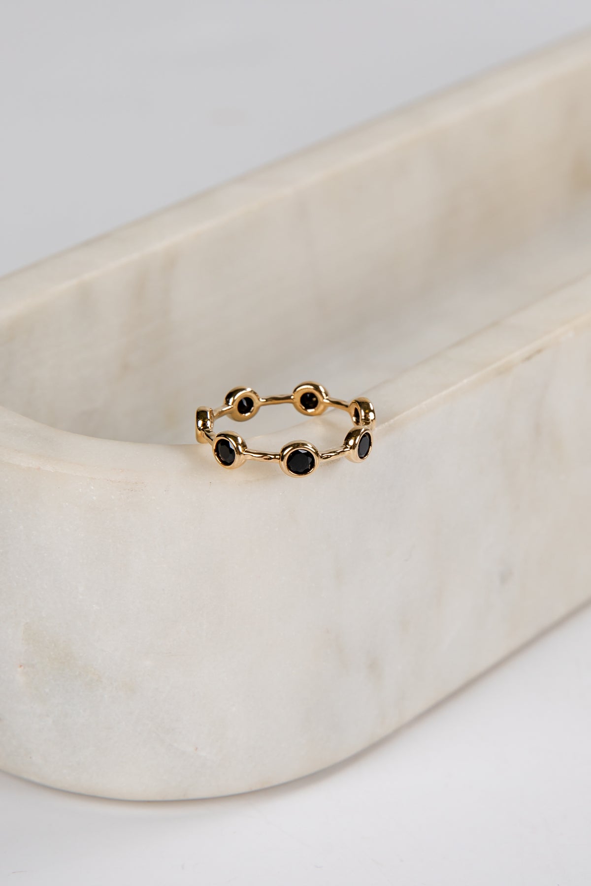 Gold ring with black stones on a marble surface