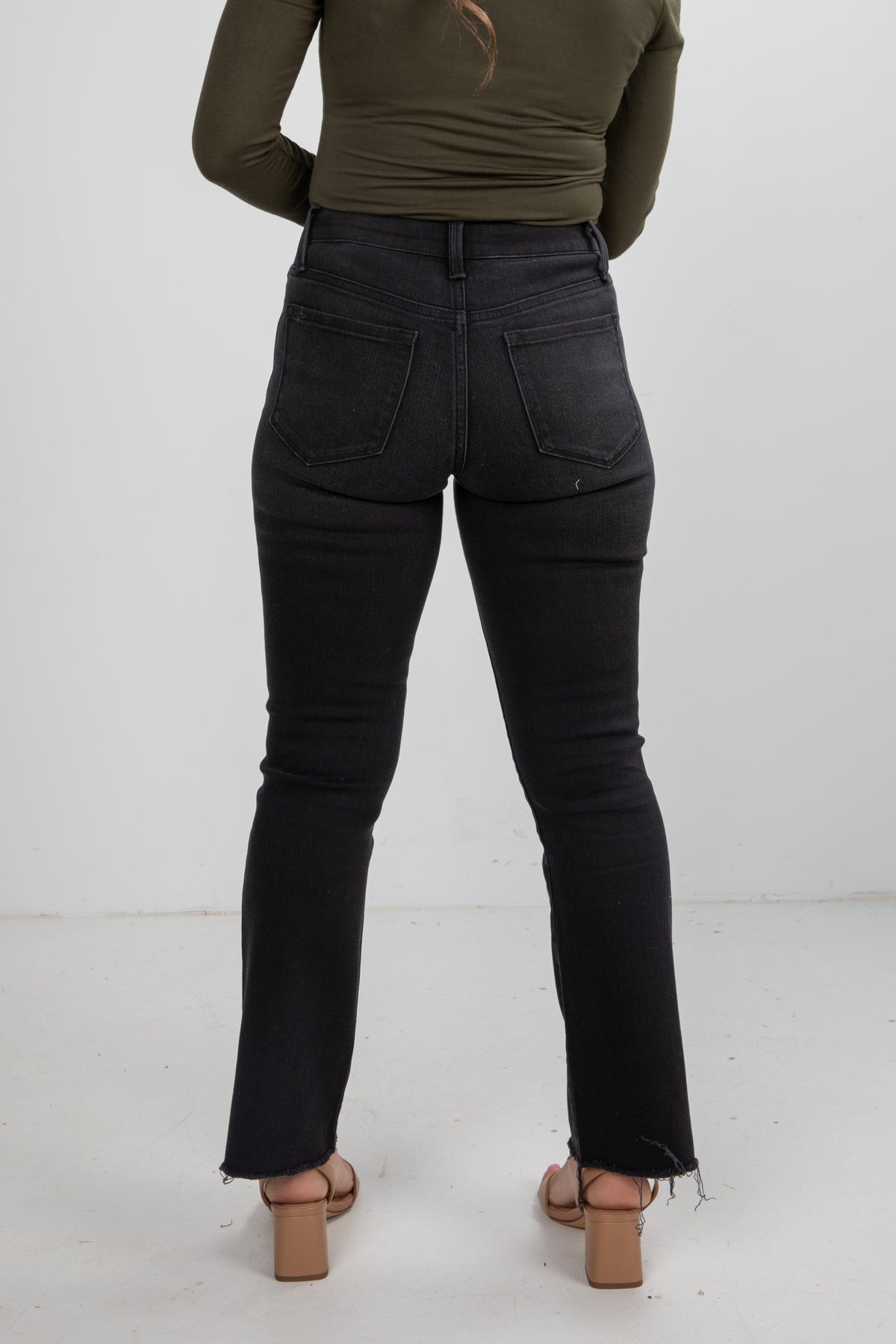 Person wearing black jeans and a green top on a white background