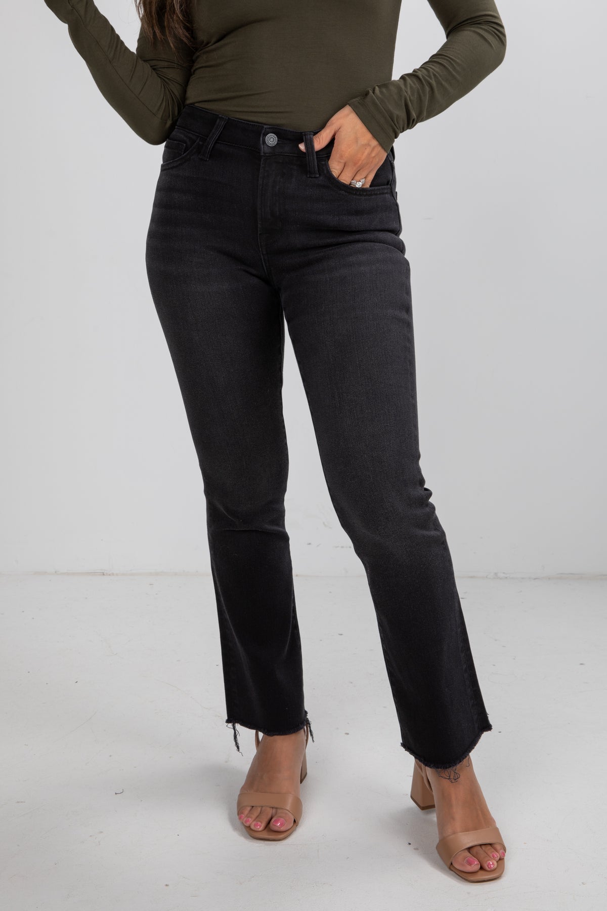 Person wearing black jeans and a green top on a white background