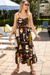 Woman in a patterned dress standing outdoors near a pool area