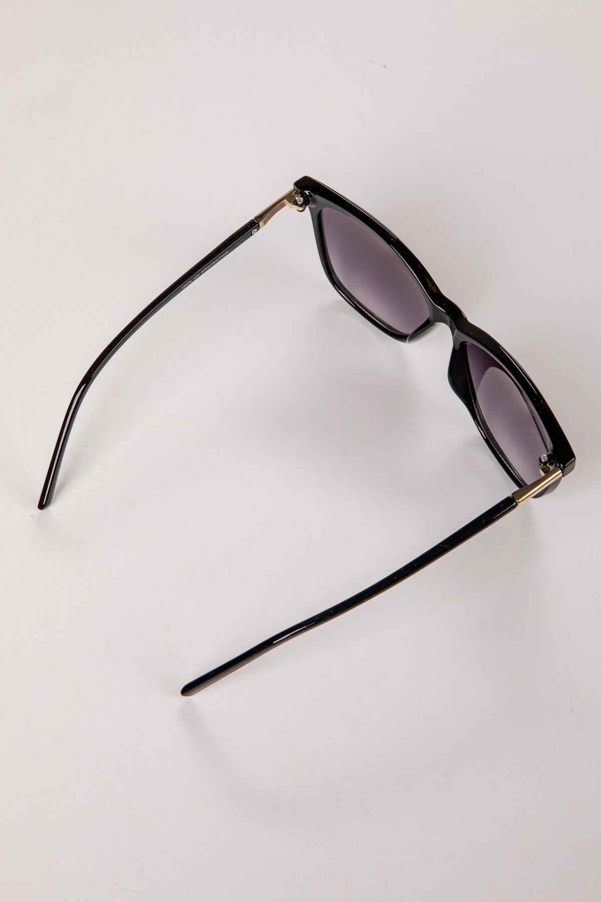 Black sunglasses with gold accents on a white background