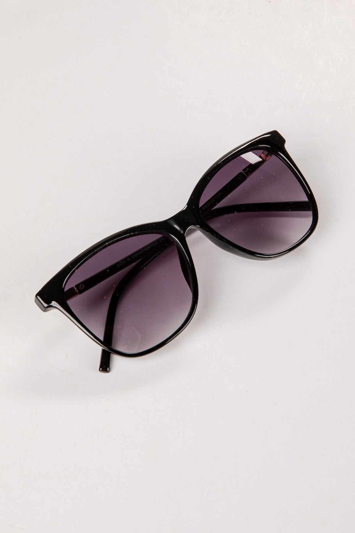Black sunglasses with purple lenses on a white background