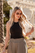 Woman with long blonde hair wearing sunglasses and a black top outdoors.
