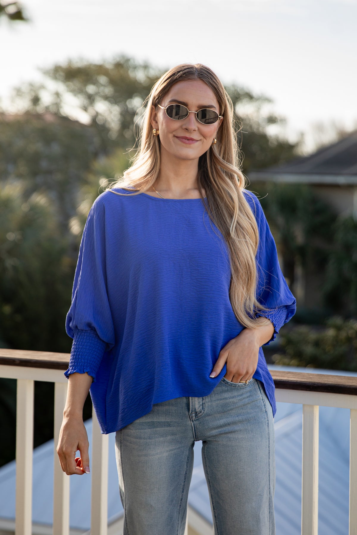Woman wearing a blue sweater and sunglasses outdoors