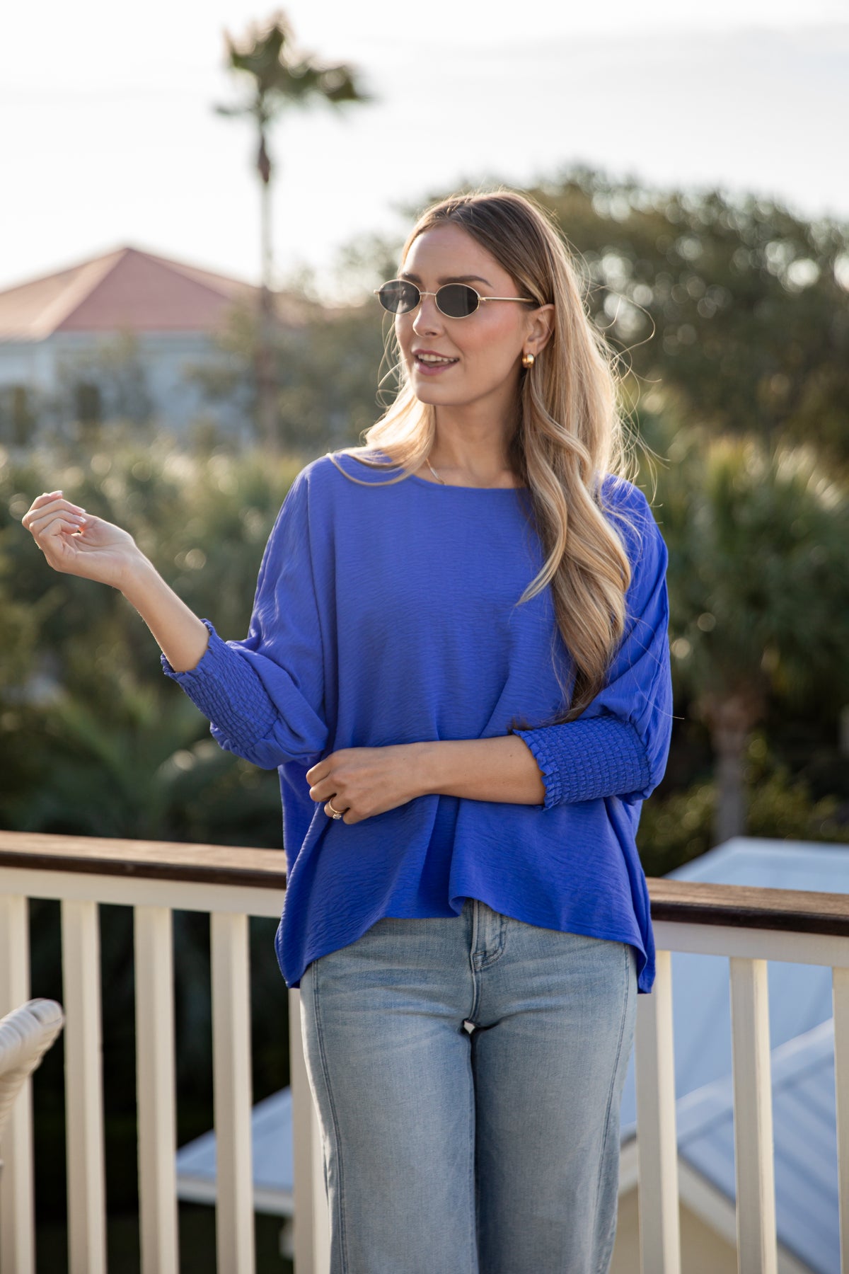 Woman wearing a blue top and sunglasses outdoors