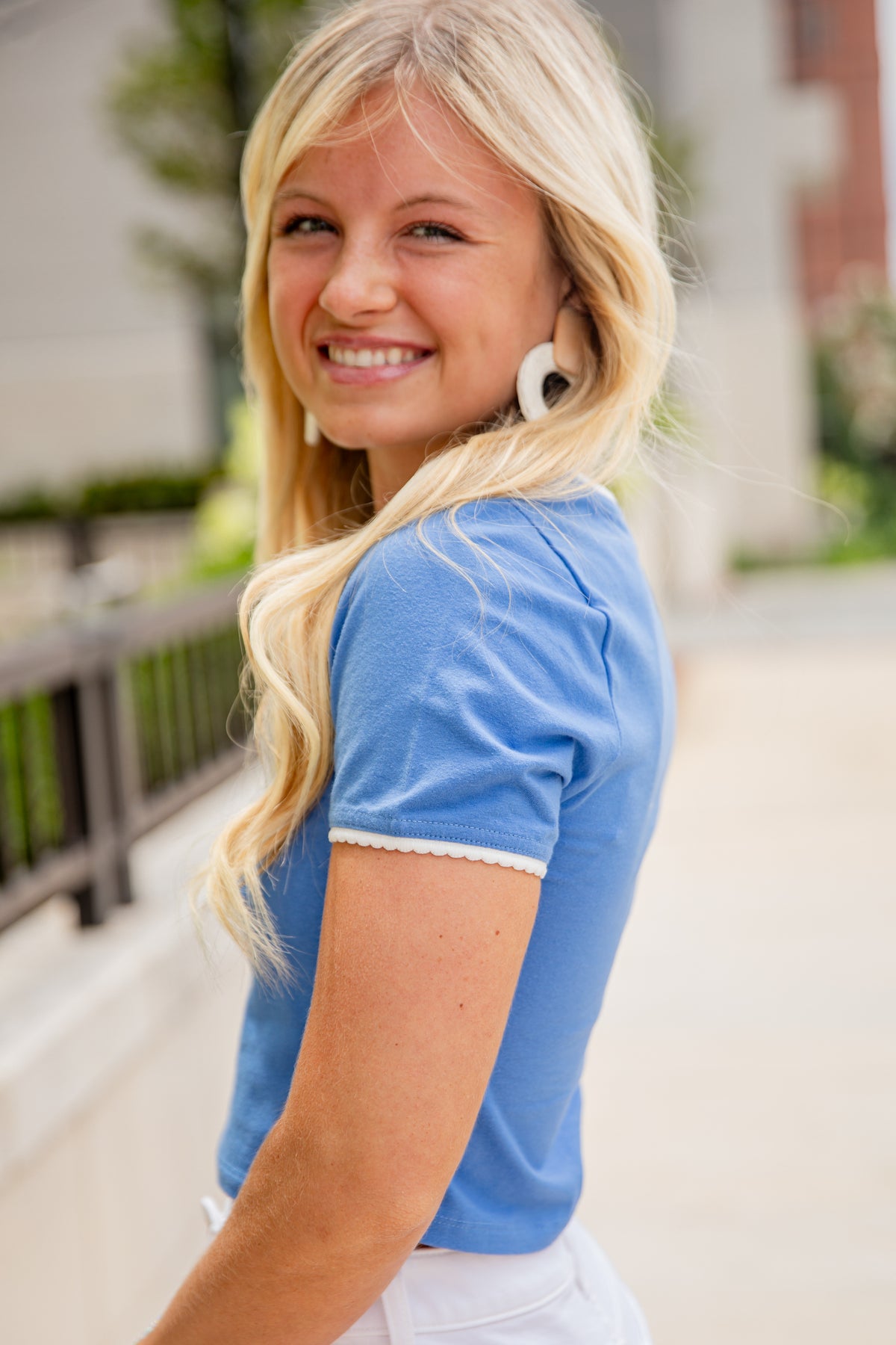 Woman wearing a blue shirt with lace trim outdoors