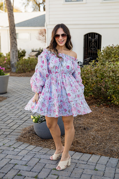 Woman wearing a floral off-shoulder dress standing on a patio.