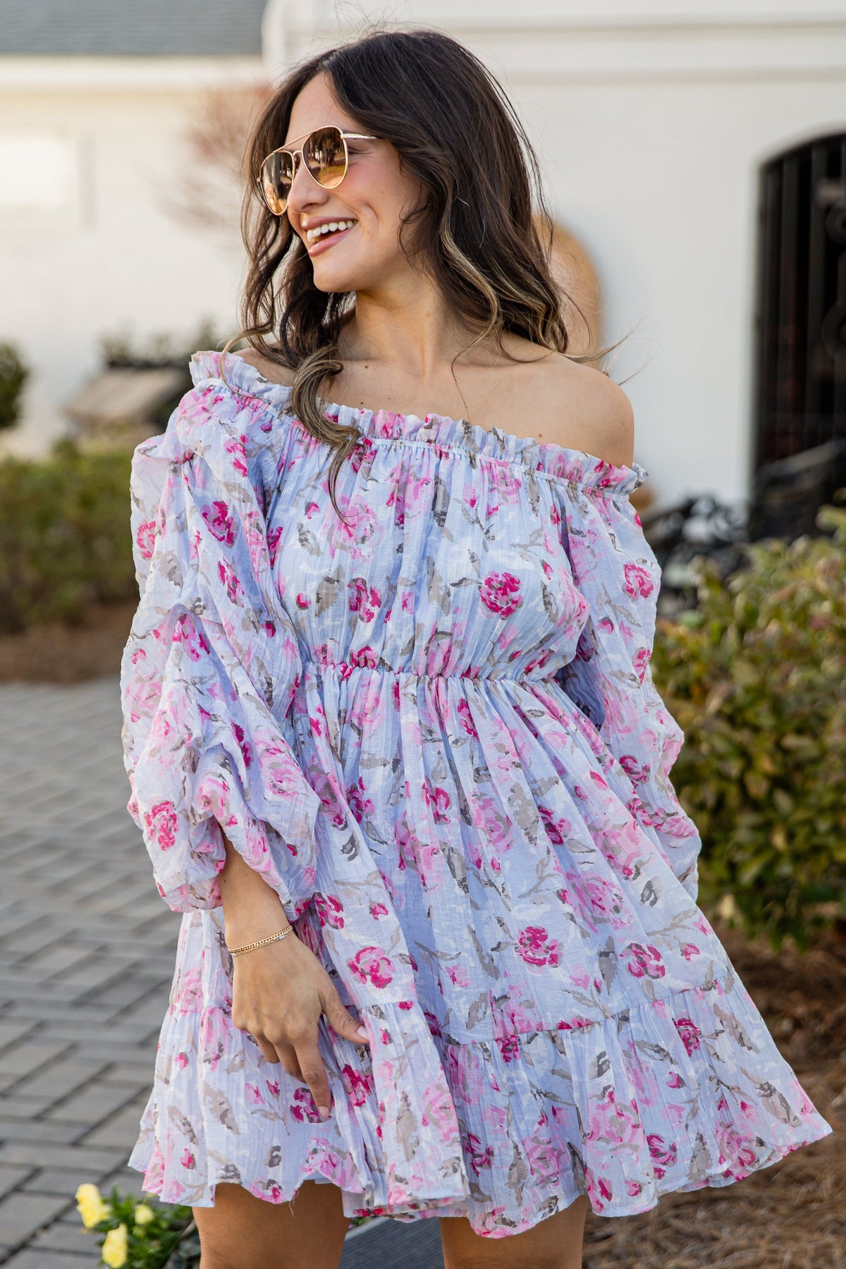 Woman wearing a floral off-shoulder dress outdoors.