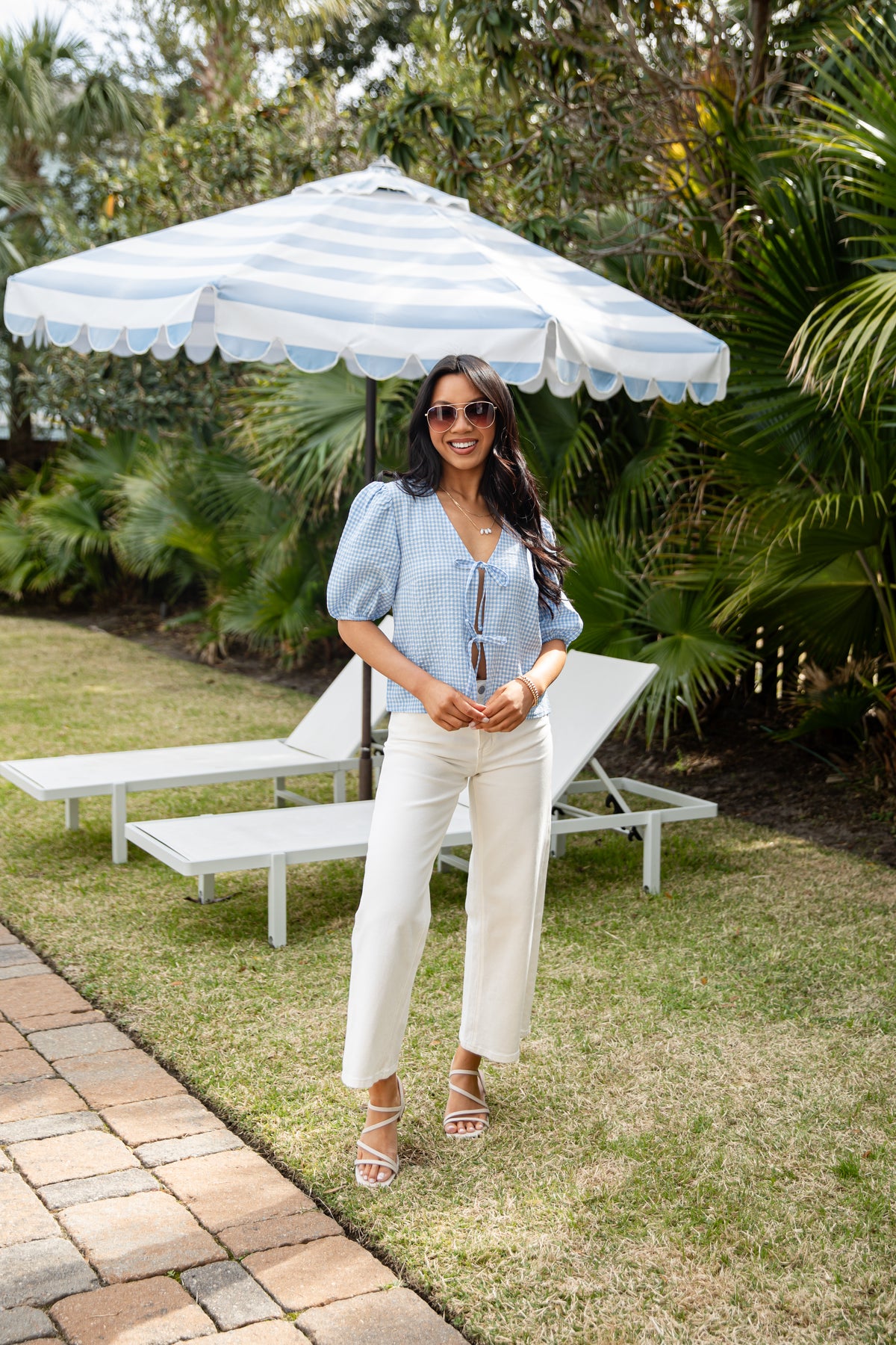 Woman standing under a striped umbrella in a garden setting