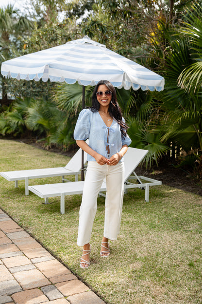 Woman standing under a striped umbrella in a garden setting