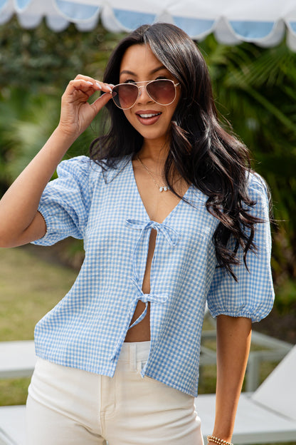 Woman wearing a blue checkered shirt and sunglasses outdoors