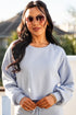 Woman wearing a light blue sweatshirt and sunglasses outdoors