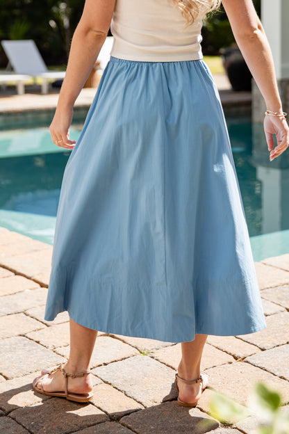 Person wearing a blue skirt by a poolside