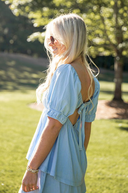 Woman in a light blue outfit standing in a park