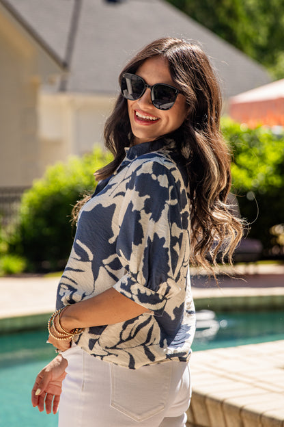 Woman wearing sunglasses and a patterned top by a poolside