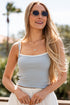 Woman wearing sunglasses and a light blue top with a blurred outdoor background
