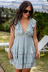 Woman wearing a light blue dress with ruffled details in an outdoor setting.