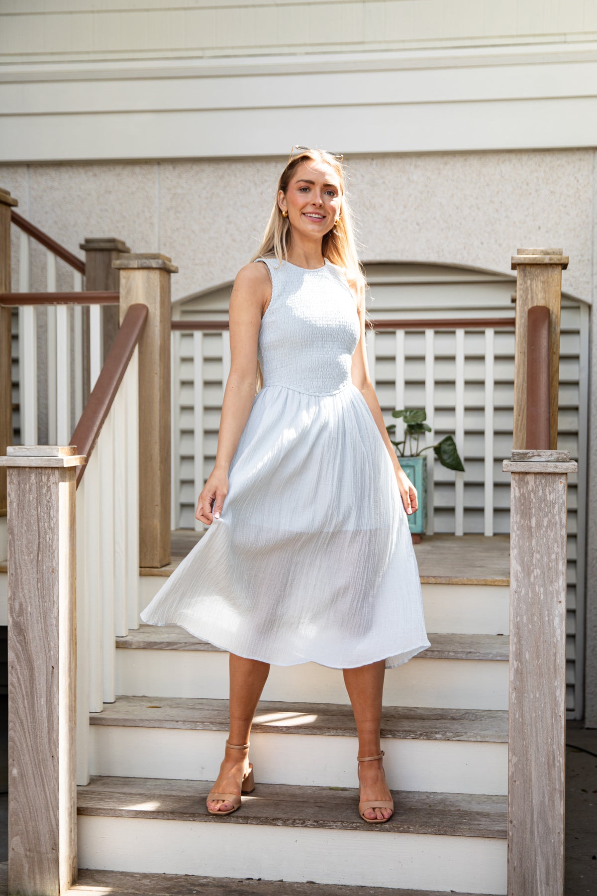 Woman in a white dress standing on wooden steps outdoors