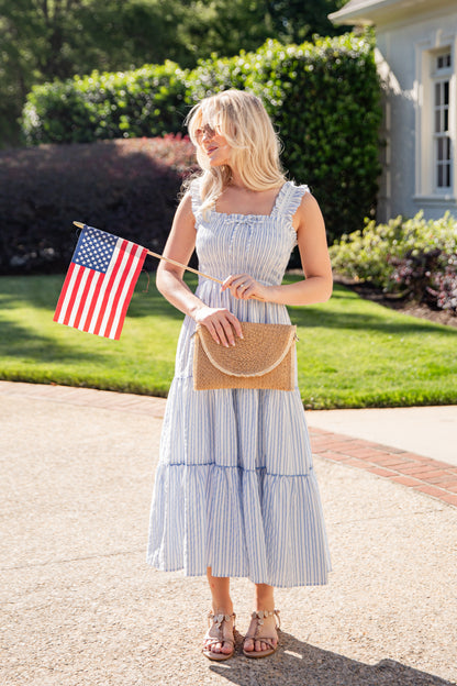 Woman in a blue striped dress holding an American flag outdoors.