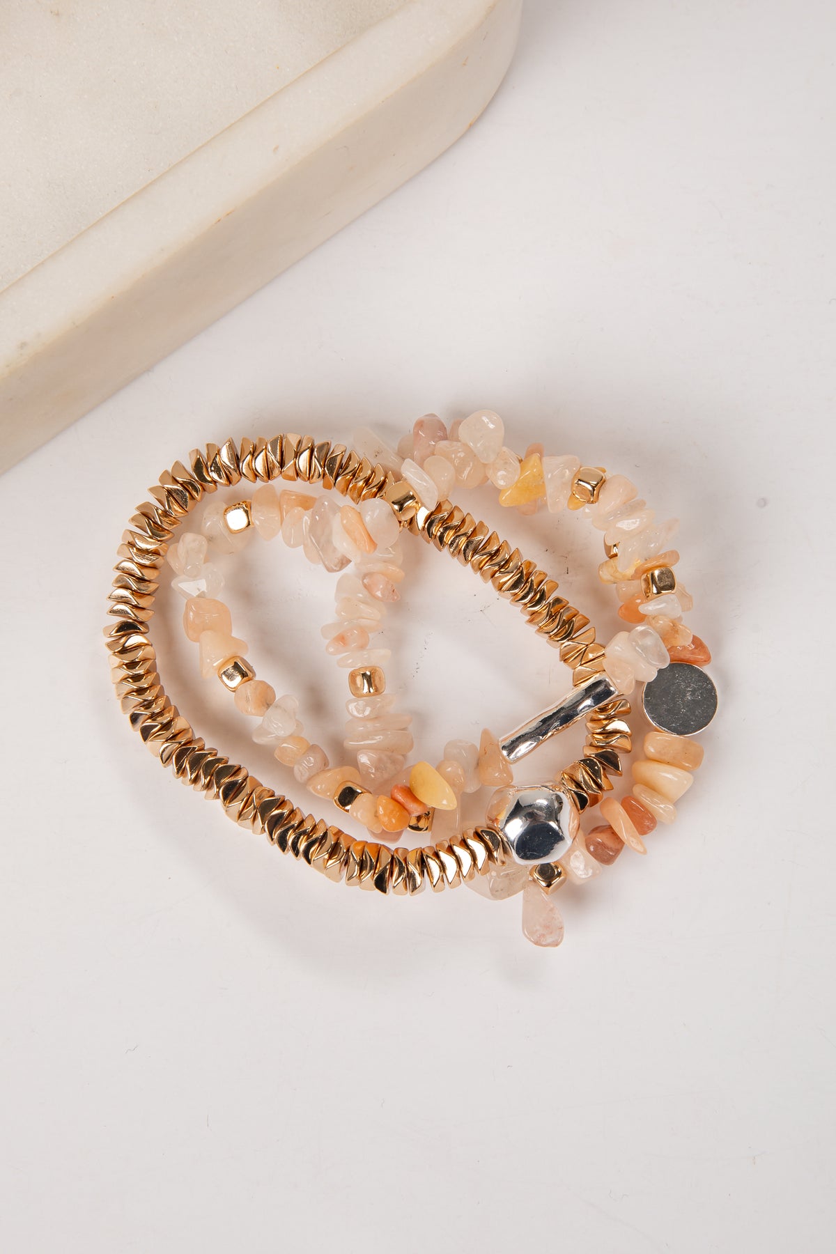 Set of beaded bracelets with gold and silver accents on a white surface