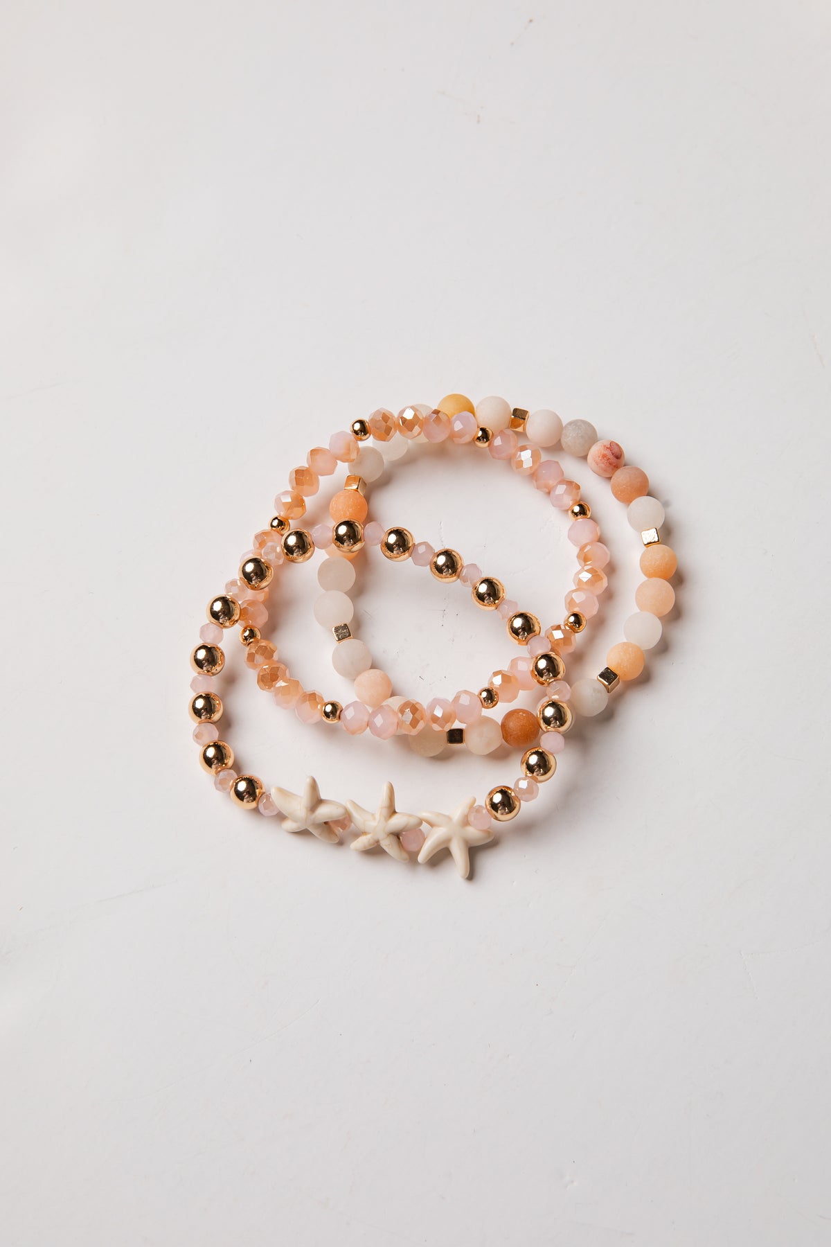 Set of beaded bracelets with starfish charm on a light gray background