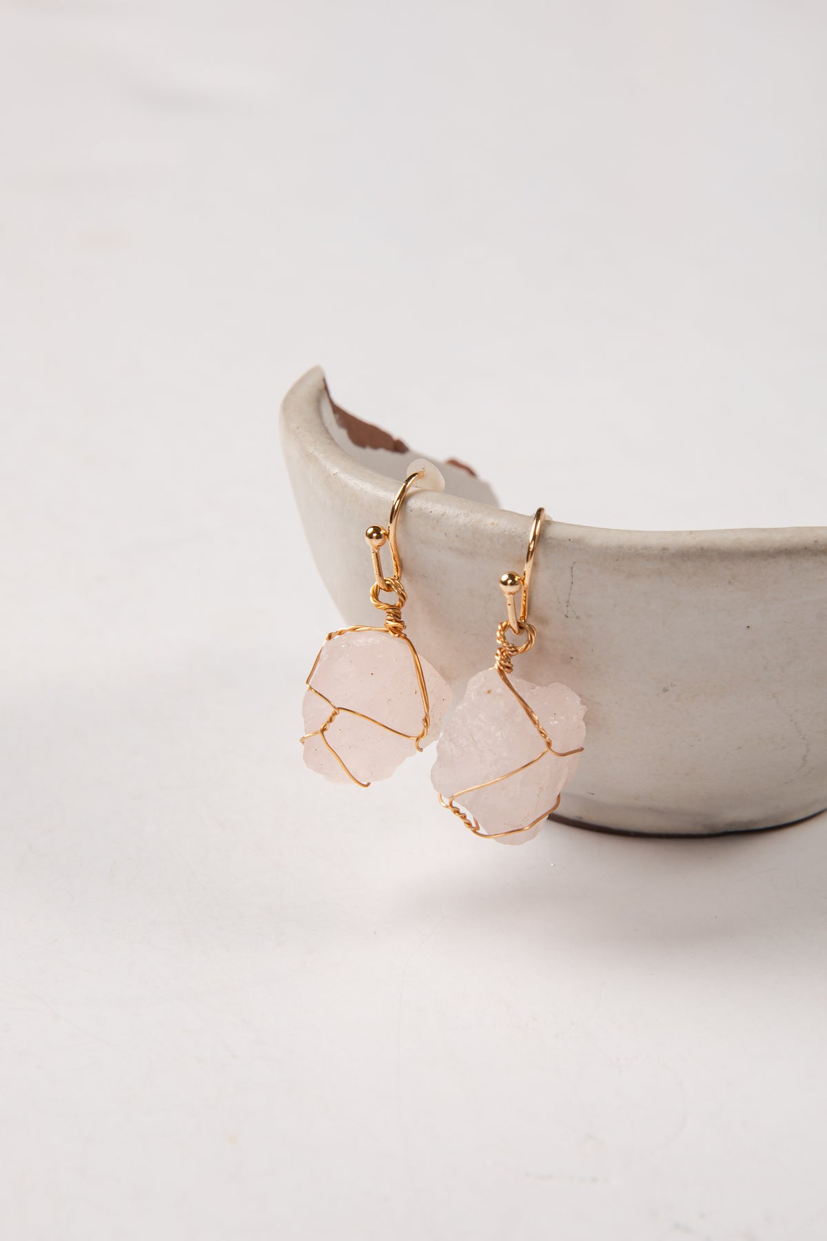 Pink stone earrings with gold wire wrapping on a white background