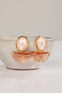 Pair of earrings with pink stones and gold accents on a white surface.