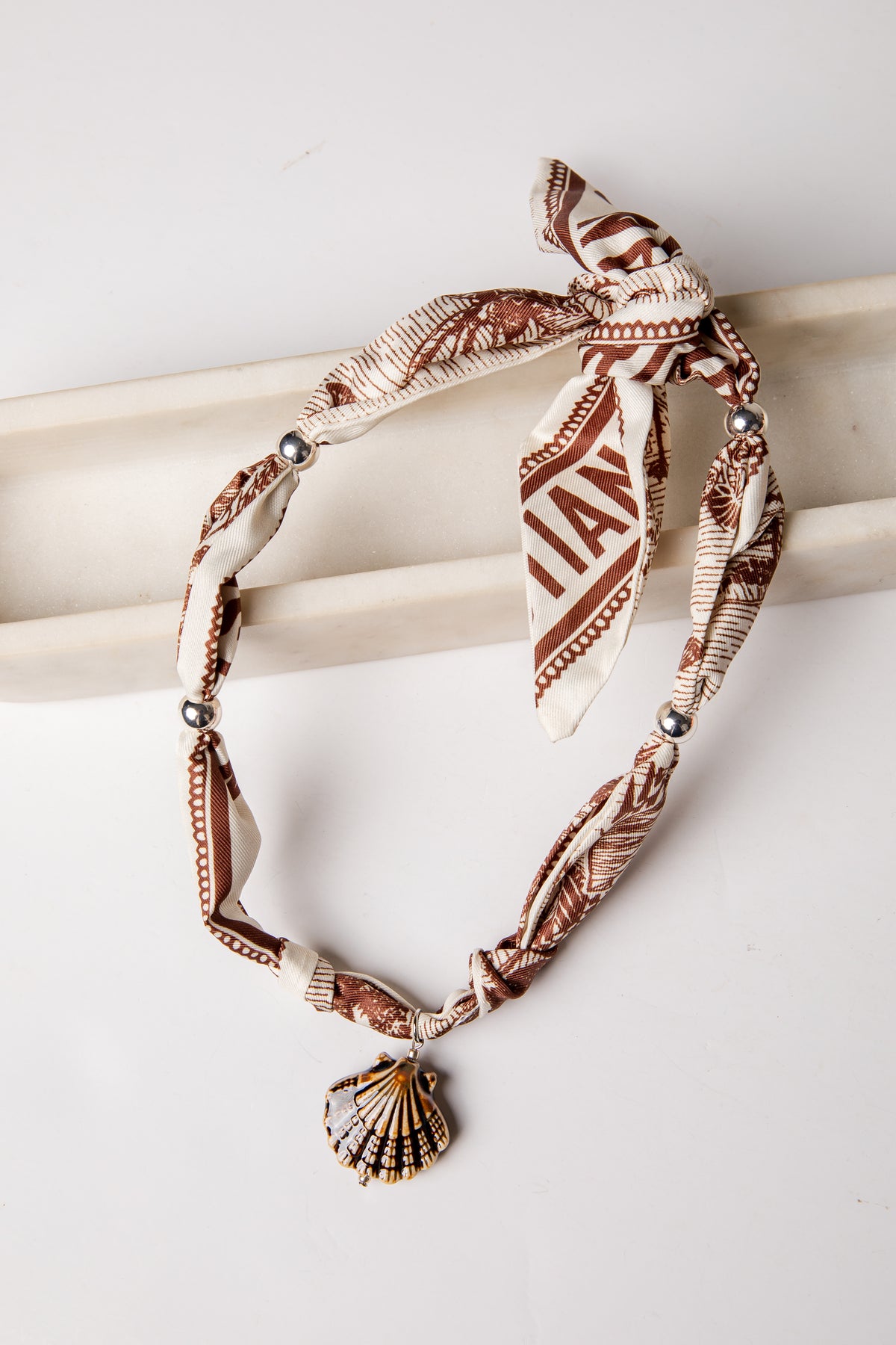 Bracelet with shell charm and patterned band on a white background