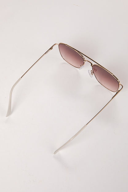 Gold-framed sunglasses with pink lenses on a white background